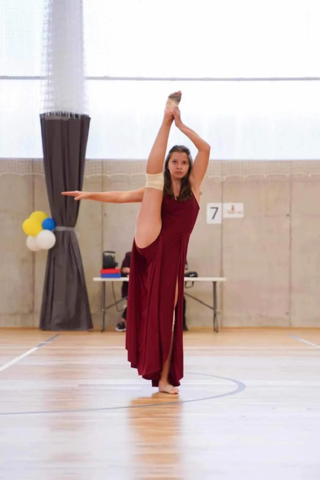 Barbora v bordových šatách drží nohu vo vertikále na súťaži